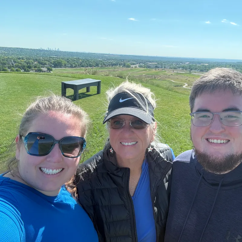 Chris with her mom and brother on a hilltop golf course